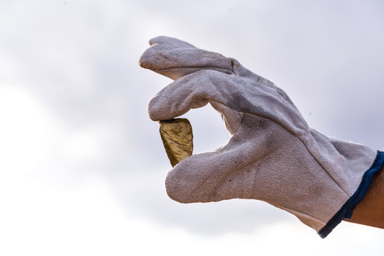 Gloved hand holding a gold nugget linked to illegal mining